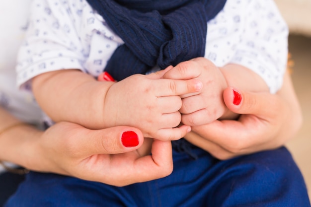 Manos del bebé de la familia. Madre sosteniendo al niño recién nacido. Primer plano de la mano del niño en los padres.