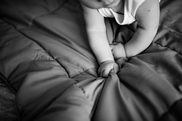 Foto manos de bebé. el niño está acostado en la cama.