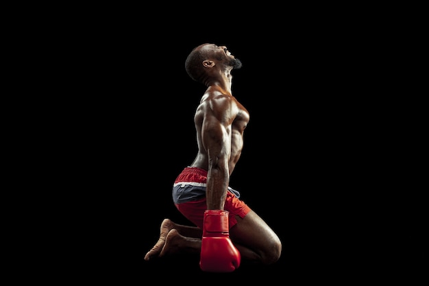 Manos de boxeador sobre fondo negro. Concepto de fuerza, ataque y movimiento. Colocar modelo afroamericano en movimiento. Atleta afro musculoso en uniforme deportivo. Hombre deportivo durante el boxeo
