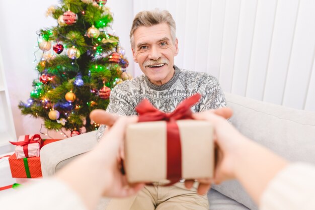 Las manos con una caja de regalo para un anciano feliz.