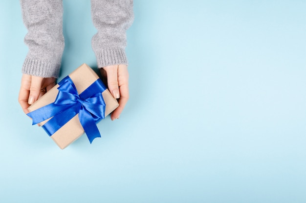 Manos con caja de regalo con cinta y lazo.