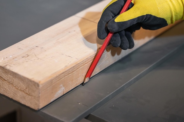 Las manos del carpintero de primer plano están trabajando con madera El carpintero marca la tabla de madera Lápiz en mano