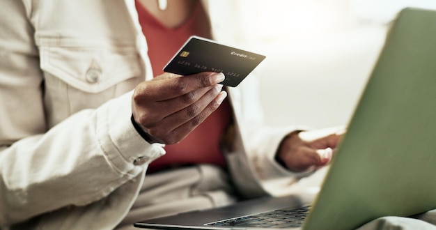 Manos en casa y mujer con tarjeta de crédito portátil y comercio electrónico con ahorros inversión y pago Apartamento persona y chica en el sofá PC y compras en línea con presupuesto de primer plano y transacciones