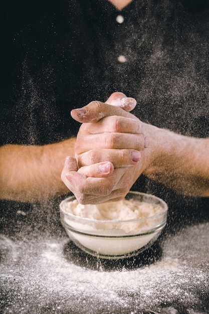 Foto las manos del chef arrojan harina sobre una mesa de madera