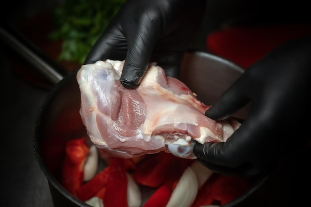 Las manos del chef con guantes negros sostienen carne cruda Profundidad de campo reducida