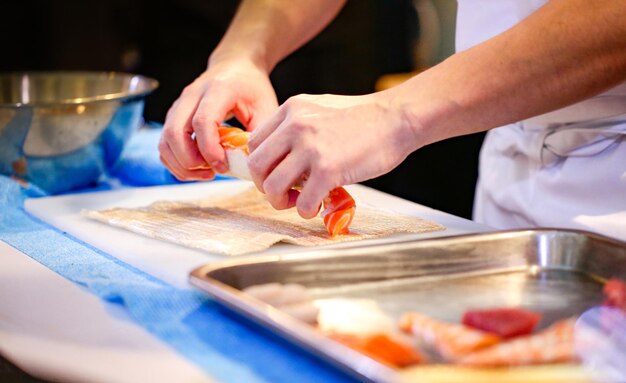 las manos del chef preparando comida japonesa el chef haciendo sushi preparando rollo de sushi Maki