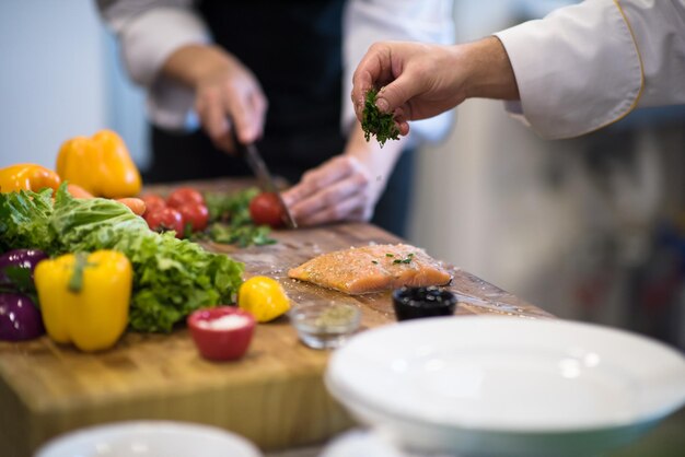 Manos del chef preparando filete de pescado salmón marinado para freír en la cocina de un restaurante