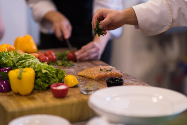 Manos del chef preparando filete de pescado salmón marinado para freír en la cocina de un restaurante