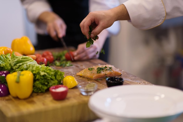 Manos del chef preparando filete de pescado salmón marinado para freír en la cocina de un restaurante