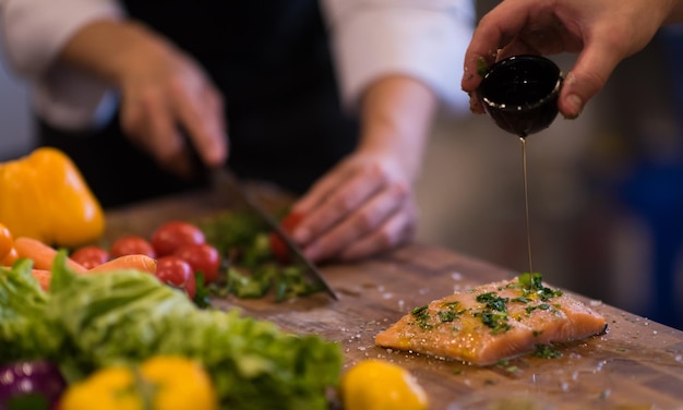 Manos del chef preparando filete de pescado salmón marinado para freír en la cocina de un restaurante