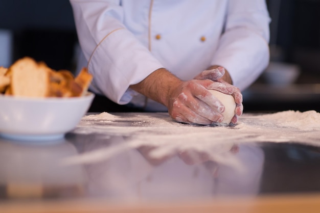 Manos del chef preparando la masa para pizza espolvoreada con harina en primer plano de la tabla