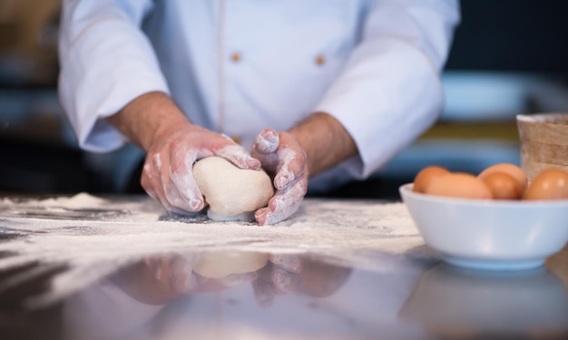 manos del chef preparando masa para pizza en la mesa espolvoreada con harina de cerca