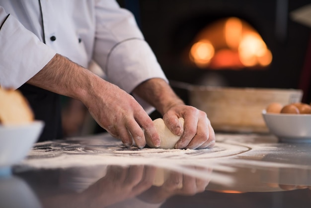 manos del chef preparando masa para pizza en la mesa espolvoreada con harina de cerca