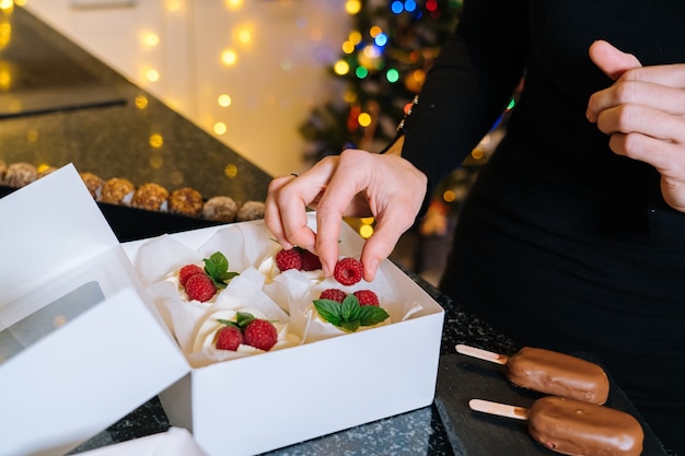 Las manos del chef sostienen cupcakes navideños caseros con fruta. Feliz Año Nuevo y feliz Navidad