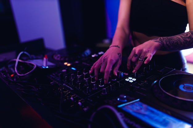 Las manos de una chica dj en el panel de control de música.