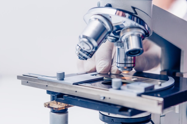 Manos científicas con primer plano de microscopio en el laboratorio