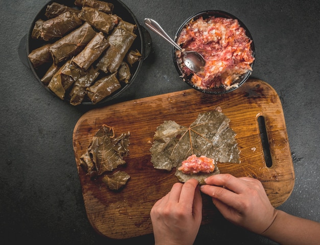 Manos cocinando dolma en mesa de corte de madera