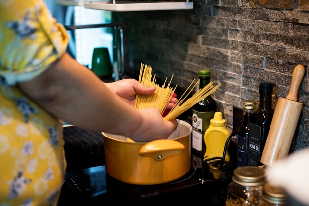 Manos cocinando pasta en una olla