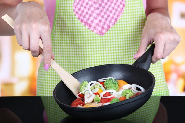 Foto manos cocinando ragout de verduras en una sartén en la cocina