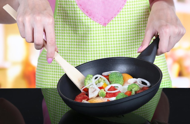 Foto manos cocinando ragú de verduras en una sartén en la cocina
