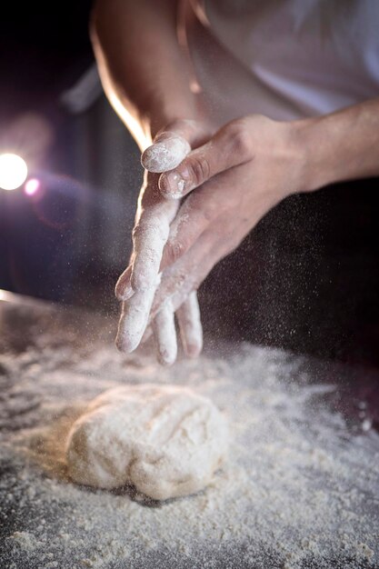 Foto las manos del cocinero amassando la masa de la pizza de cerca