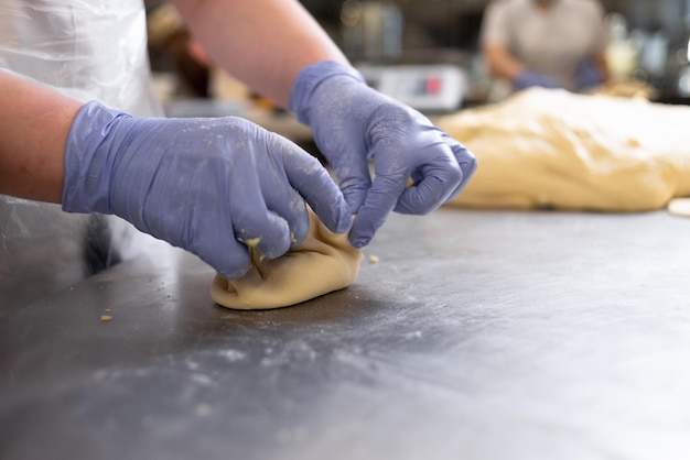 Las manos del cocinero hacen pasteles con relleno de masa de levadura Pasteles crudos en una placa de metal Trabajo en la confitería