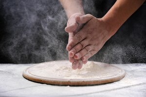 Foto manos del cocinero y harina sobre un fondo oscuro. cocinar comida manos en harina