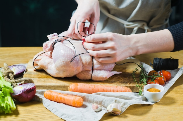 Manos del cocinero que preparan la granja de pollo cruda.