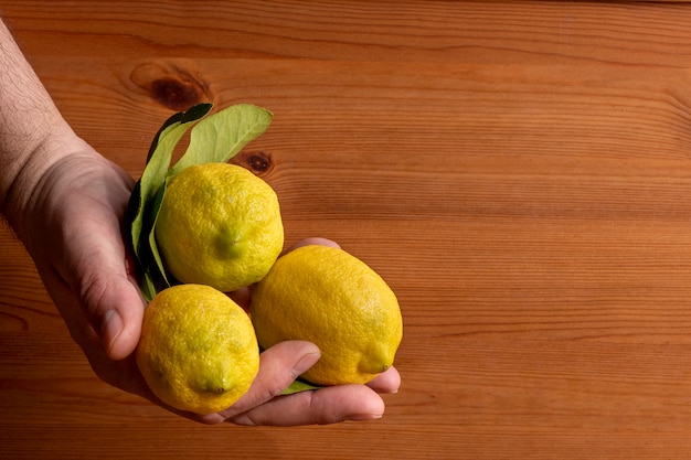 Manos con Limones con Fondo de Madera.