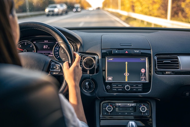 Las manos del conductor de la mujer en el volante dentro del coche