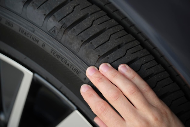 Manos de la conductora inspeccionando el neumático de la rueda de su nuevo automóvil Concepto de seguridad del vehículo
