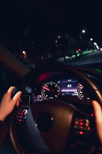 Las manos de los conductores en el volante de un coche en la conducción nocturna