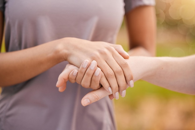 Foto manos de confianza y apoyo con amigos al aire libre juntos en una muestra de unidad, solidaridad o consuelo amor, empatía y cuidado con una mujer consolando o consolando a una amiga afuera por compasión