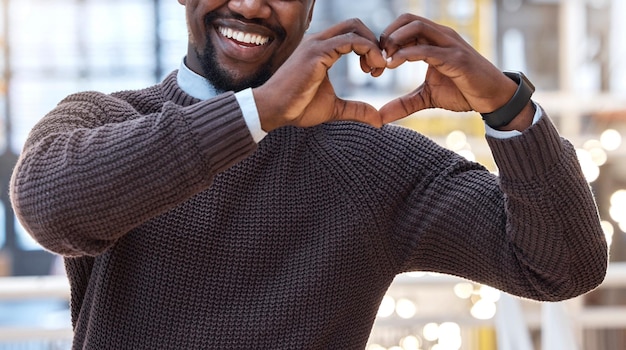 Manos corazón y hombre negro mostrando signo de gesto de amor o símbolo sintiéndose feliz apoyo emocionado en una oficina Empleado de cuidado y hombre de negocios con emoji e icono de forma amorosa o abundante en el trabajo