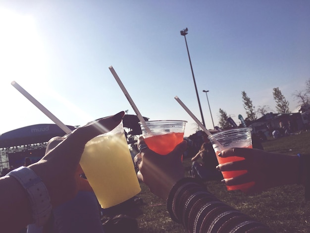 Foto manos cortadas de amigos brindando contra el cielo despejado