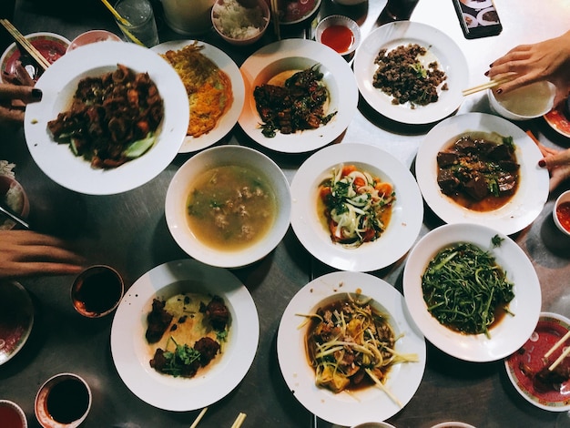 Manos cortadas de amigos con comida servida en la mesa