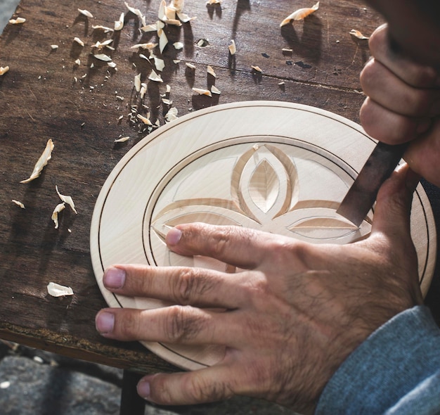 Foto manos cortadas de un artista tallando madera en un taller