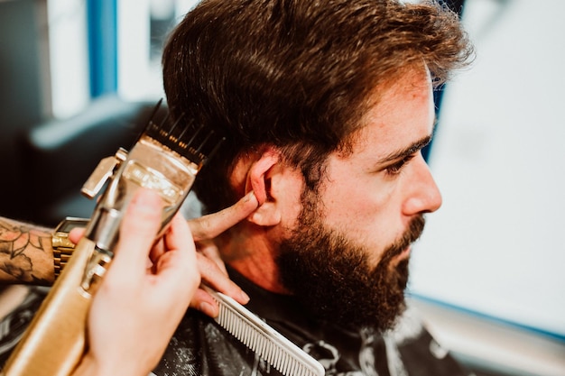 Manos cortadas de un barbero arreglando a un cliente en el salón