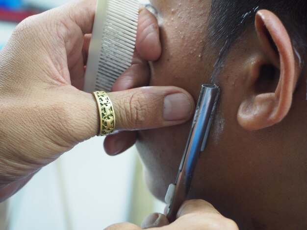 Foto manos cortadas de barbero cortando la barba de un cliente en el salón