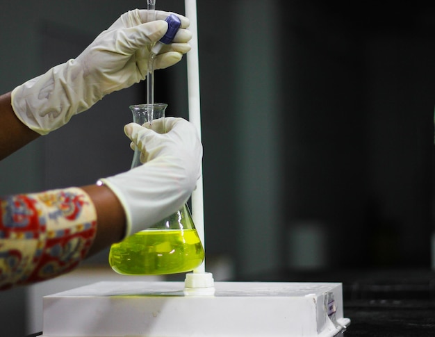 Foto manos cortadas de un científico examinando sustancias químicas en el laboratorio