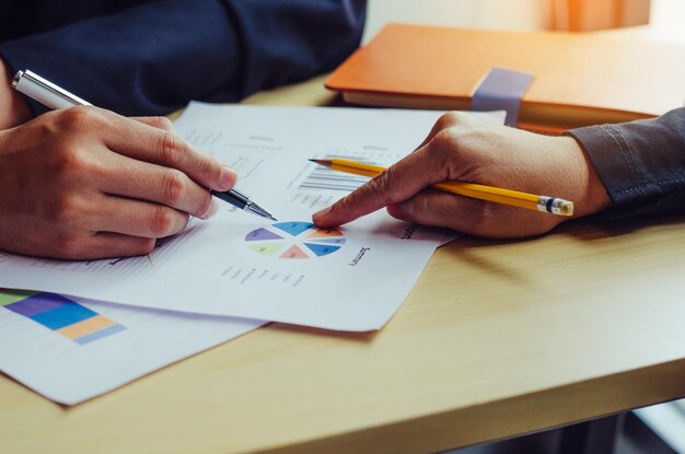 Manos cortadas de colegas de negocios trabajando en un escritorio en la oficina