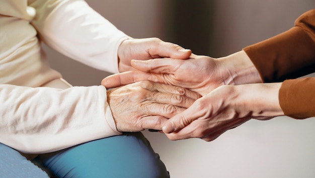 Manos cortadas de perto de mãos que ajudam cuidados domiciliares de idosos Mãe e filha Saúde mental