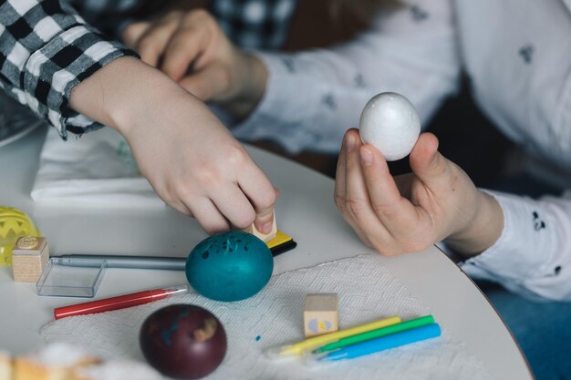 Foto manos cortadas decorando el huevo de pascua en la mesa