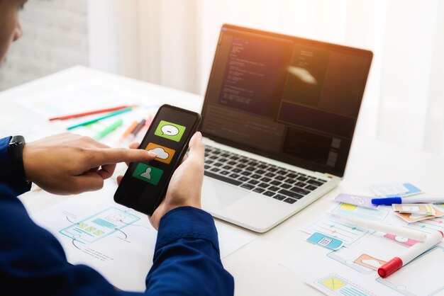 Manos cortadas de un desarrollador de software usando un teléfono móvil en la mesa