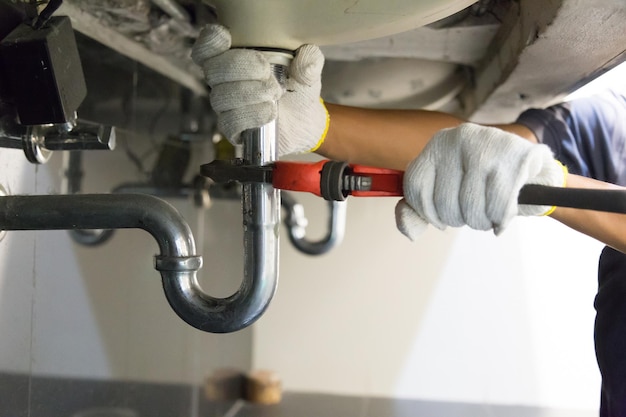 Foto manos cortadas de un fontanero reparando tuberías