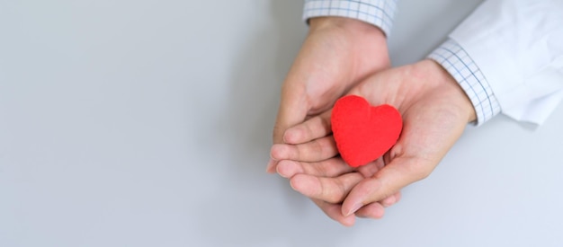 Manos cortadas con forma de corazón rojo en la mesa