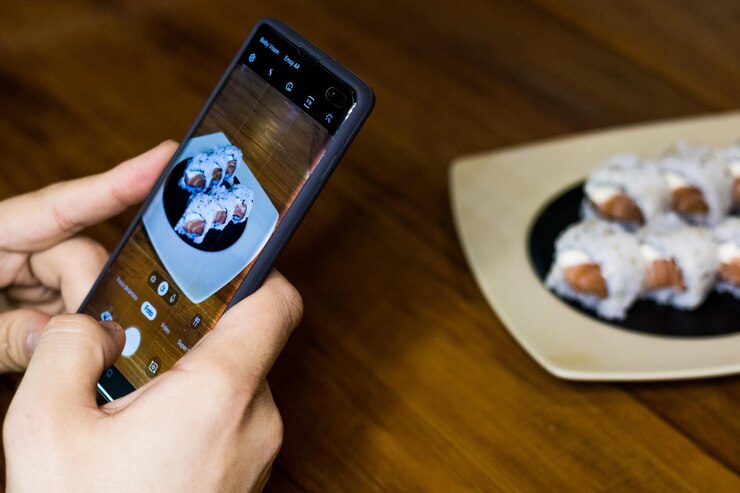Foto manos cortadas fotografiando comida servida en la mesa con teléfono móvil