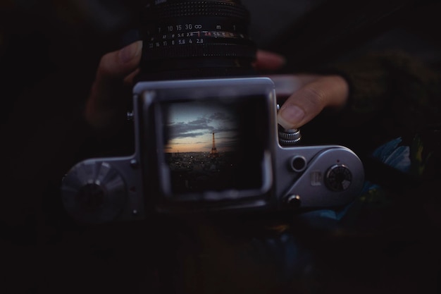 Manos cortadas fotografiando la Torre Eiffel durante la puesta de sol