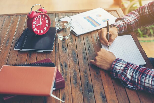 Manos cortadas de un hombre escribiendo en un libro