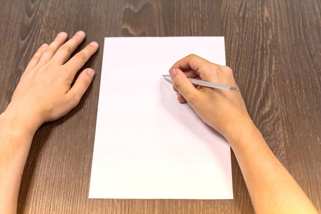 Foto manos cortadas de un hombre escribiendo en papel en blanco en la mesa